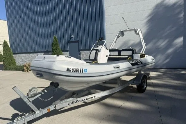 Slide: The Image of 2025 Highfield Velox 420 boat on trailer, parked outdoors near a blue building. - 13