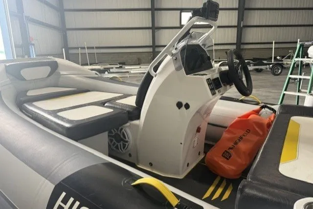 Slide: The Image of 2025 Highfield Velox 420 boat interior with steering console and seating in a warehouse. - 11