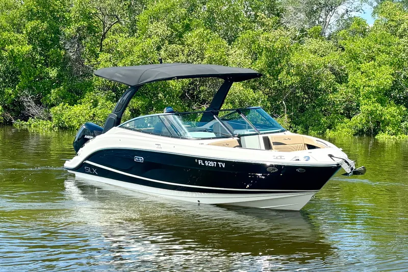 Slide: The Image of 2023 Sea Ray SLX 260 Outboard boat on calm water, surrounded by lush greenery. - 4