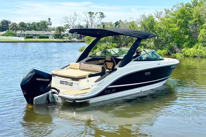 Slide: The Image of 2023 Sea Ray SLX 260 Outboard boat on calm water, featuring sleek design and Mercury engine. - 2
