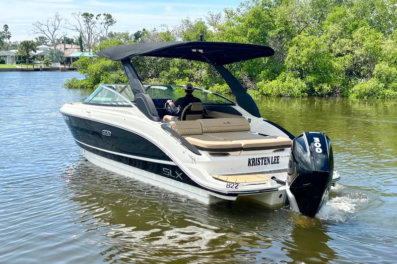 Slide: The Image of 2023 Sea Ray SLX 260 Outboard cruising on a scenic river with lush greenery. - 3