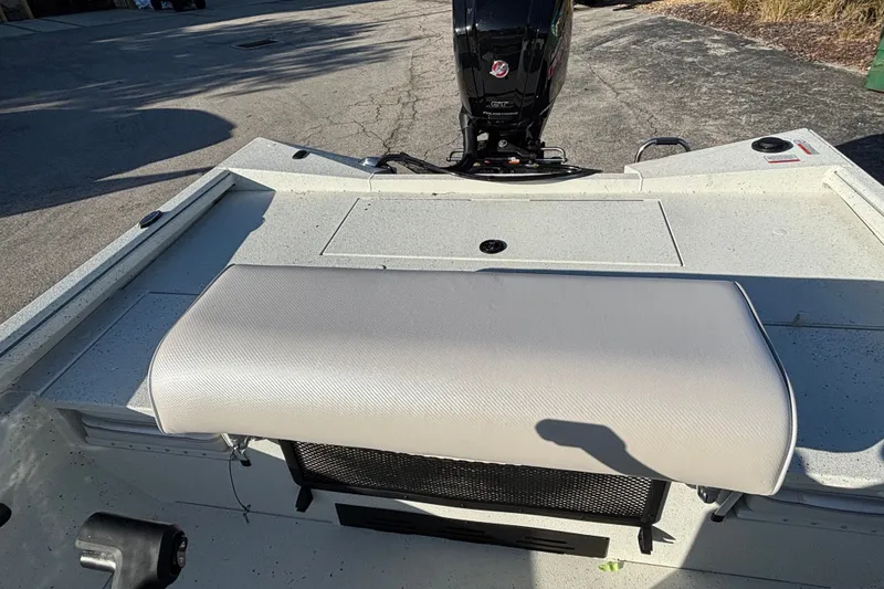 Slide: The Image of 2027 Ranger RB190 boat interior with cushioned seating and motor, parked on pavement. - 7
