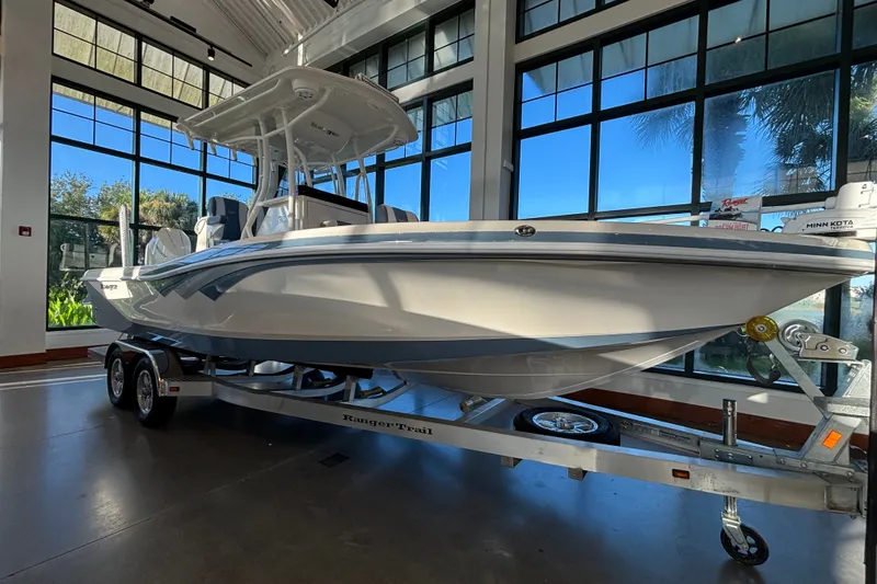 Slide: The Image of 2025 Ranger 2600 Bay boat displayed indoors on a trailer. - 1