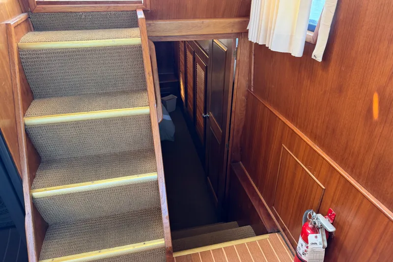 Slide: The Image of Staircase inside 1984 Californian 43 Cockpit MY yacht with wooden paneling and fire extinguisher. - 39