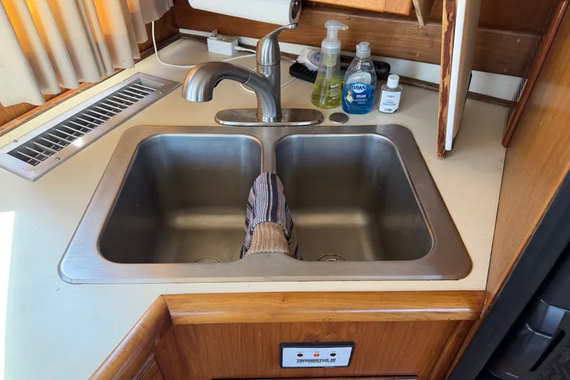 Slide: The Image of Double sink in 1984 Californian 43 Cockpit MY yacht kitchen with cleaning supplies. - 23