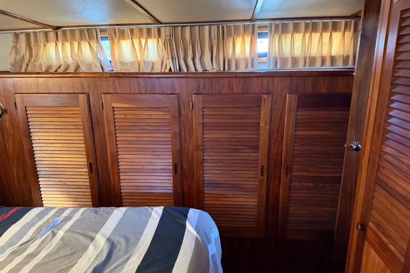 Slide: The Image of Interior of 1984 Californian 43 Cockpit MY with wooden cabinets and striped bedding. - 44