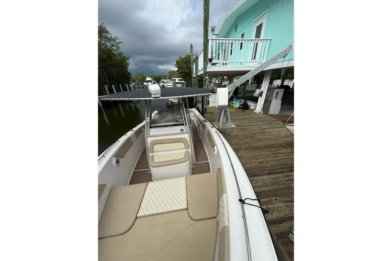 Slide: The Image of 2004 Grady-White Canyon 306 boat docked beside a turquoise house under cloudy skies. - 35