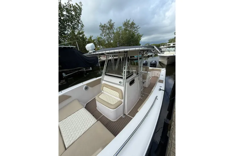 Slide: The Image of 2004 Grady-White Canyon 306 boat with cushioned seating, docked near trees and other boats. - 14