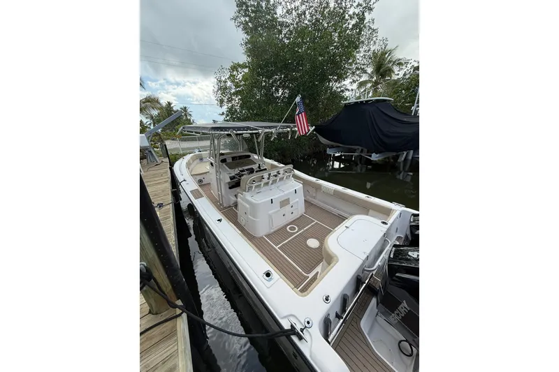 Slide: The Image of 2004 Grady-White Canyon 306 boat docked, featuring spacious deck and American flag. - 10