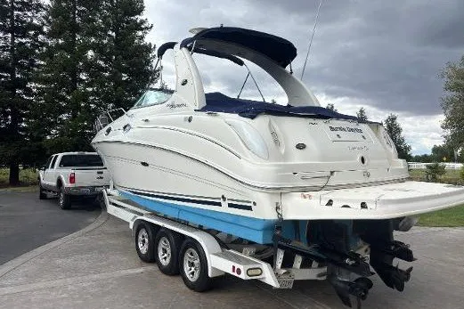 Slide: The Image of 2005 Sea Ray Sundancer 280 boat on trailer, parked near trees and cloudy sky. - 10