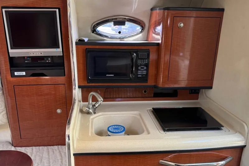 Slide: The Image of 2005 Sea Ray Sundancer 280 interior kitchen with microwave, sink, and TV. - 9