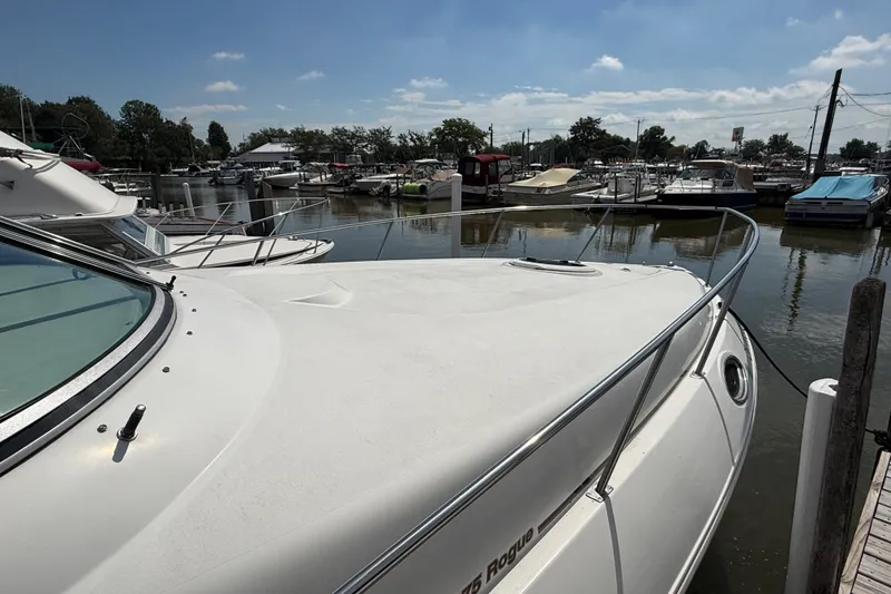 Slide: The Image of 1999 Cruisers Yachts 3075 Rogue docked at a marina under a clear blue sky. - 4