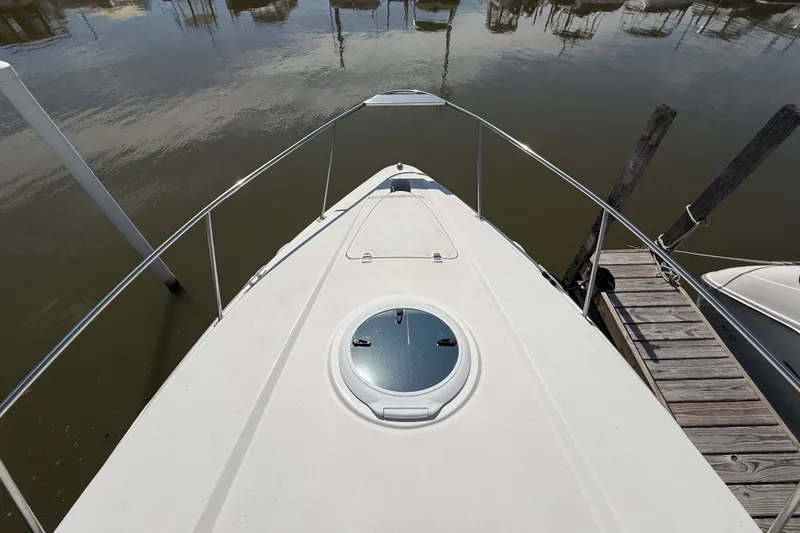 Slide: The Image of 1999 Cruisers Yachts 3075 Rogue bow view at dock, featuring sleek design and hatch. - 19