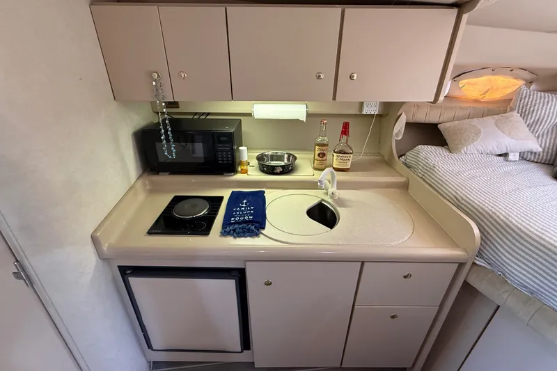 Slide: The Image of Compact yacht kitchenette with stove, sink, microwave, and liquor bottles in a 1999 Cruisers Yachts 3075 Rogue. - 35