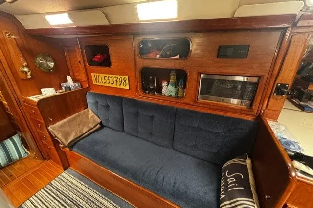 Slide: The Image of Interior of a 1973 C&C 48 sailboat with blue sofa and wooden cabinetry. - 14