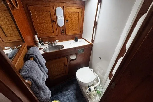 Slide: The Image of 1973 C&C 48 yacht bathroom with wooden cabinets, sink, and marine toilet. - 17