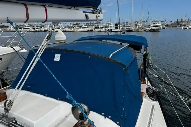Slide: The Image of 1973 C&C 48 sailboat with blue canvas cover docked in marina. - 44