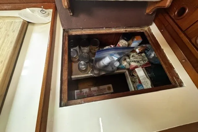 Slide: The Image of Storage compartment on a 1973 C&C 48 yacht, filled with canned goods and snacks. - 22
