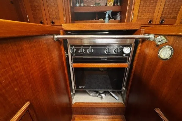 Slide: The Image of Wooden interior of a 1973 C&C 48 yacht featuring a built-in oven and storage cabinets. - 20