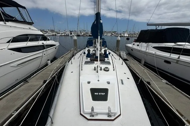 Slide: The Image of 1973 C&C 48 sailboat docked between yachts in a marina under cloudy skies. - 40