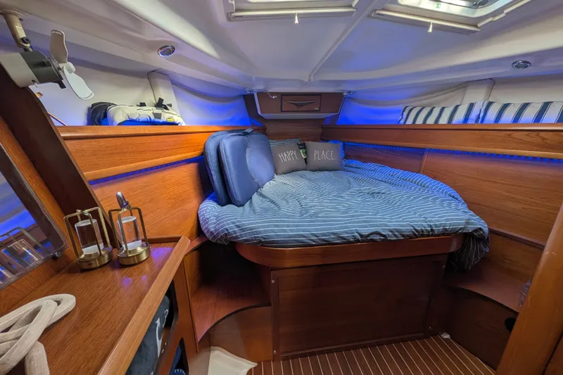 Slide: The Image of Cozy cabin interior of 2006 Jeanneau Sun Odyssey 45 with blue lighting and striped bedding. - 39