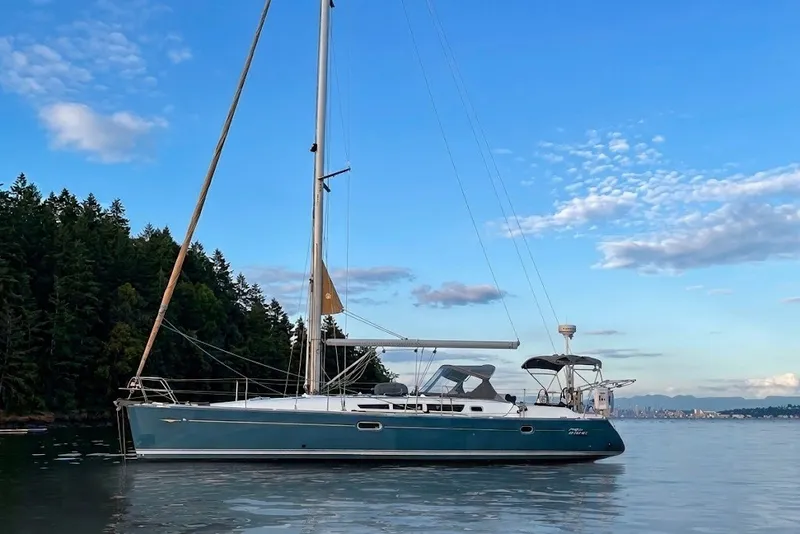 The Image of 2006 Jeanneau Sun Odyssey 45 sailboat on calm water, with forested shoreline and blue sky. - 0