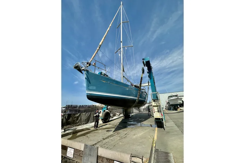 Slide: The Image of 2006 Jeanneau Sun Odyssey 45 sailboat being lifted at a marina under clear blue skies. - 52