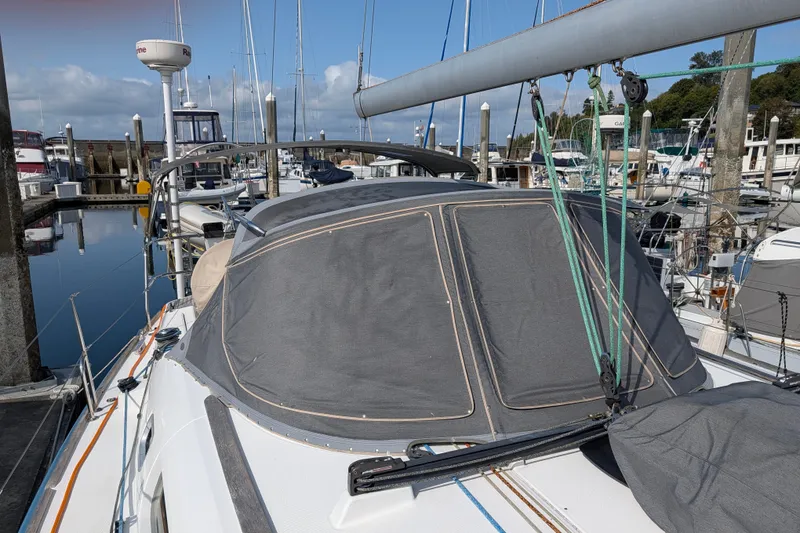 Slide: The Image of 2006 Jeanneau Sun Odyssey 45 sailboat docked at a marina, featuring a covered cockpit. - 10