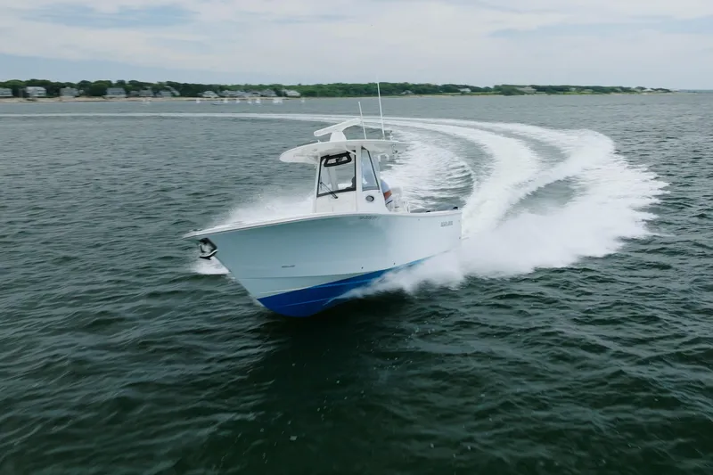 The Image of 2021 Regulator 28 Forward Seating boat cruising on open water, creating a dynamic wake. - 1