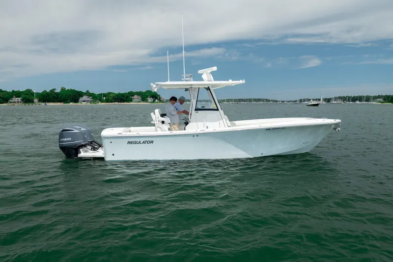 Slide: The Image of 2021 Regulator 28 Forward Seating boat on calm water with scenic shoreline background. - 7