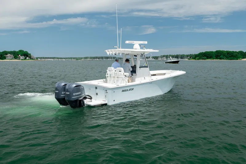 Slide: The Image of 2021 Regulator 28 Forward Seating boat cruising on a calm lake with twin Yamaha engines. - 8