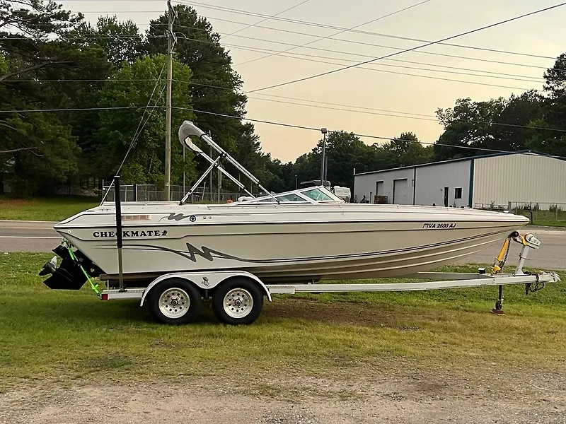The Image of A white 1995 Checkmate Persuader 261 boat on a trailer, parked on grass. - 0