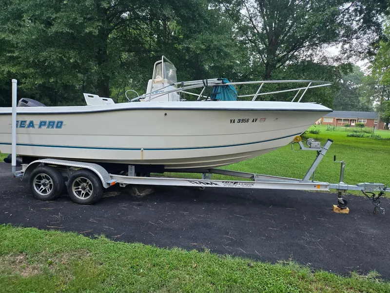 Slide: The Image of A white 1999 Sea Pro 210 Center Console boat on a trailer in a green yard. - 1