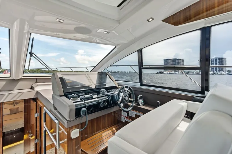 Slide: The Image of Interior view of 2022 Cruisers Yachts 54 Cantius helm with modern controls and waterfront backdrop. - 50