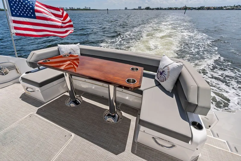 Slide: The Image of 2022 Cruisers Yachts 54 Cantius deck with table, seating, and American flag. - 31