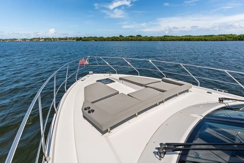 Slide: The Image of 2022 Cruisers Yachts 54 Cantius on water, featuring spacious deck and sun loungers. - 21