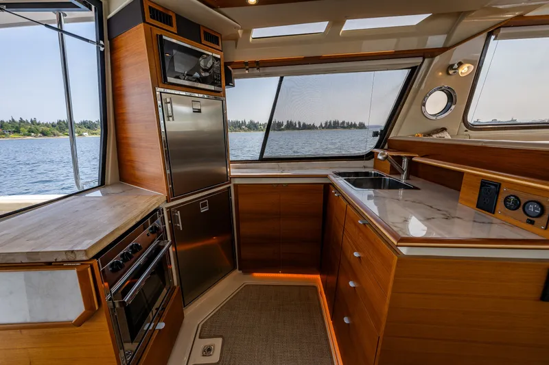 Slide: The Image of Luxurious 2020 Ranger Tugs R-41 CB yacht kitchen with modern appliances and scenic water view. - 19