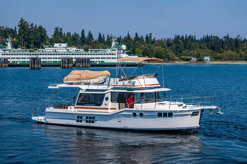 Slide: The Image of 2020 Ranger Tugs R-41 CB cruising on a scenic waterway with ferries in the background. - 2