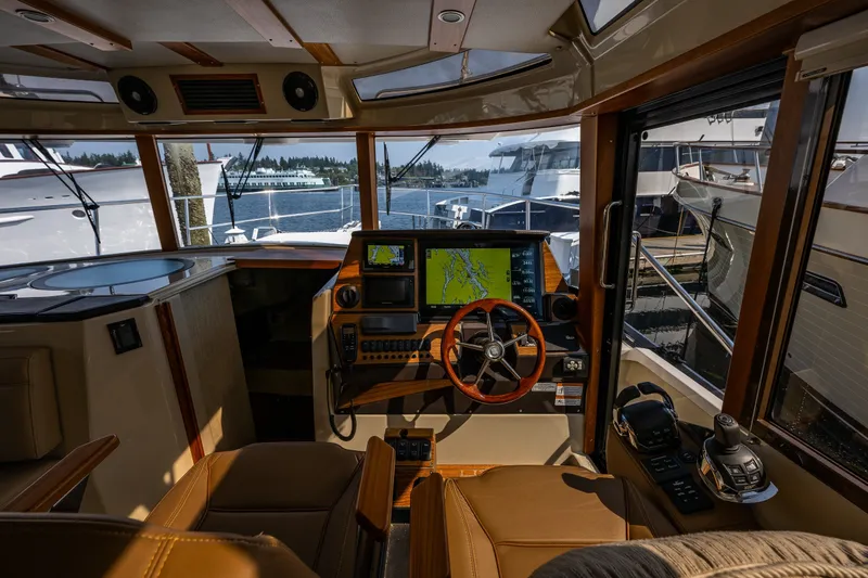 Slide: The Image of Interior view of 2020 Ranger Tugs R-41 CB helm with navigation equipment and scenic marina backdrop. - 25