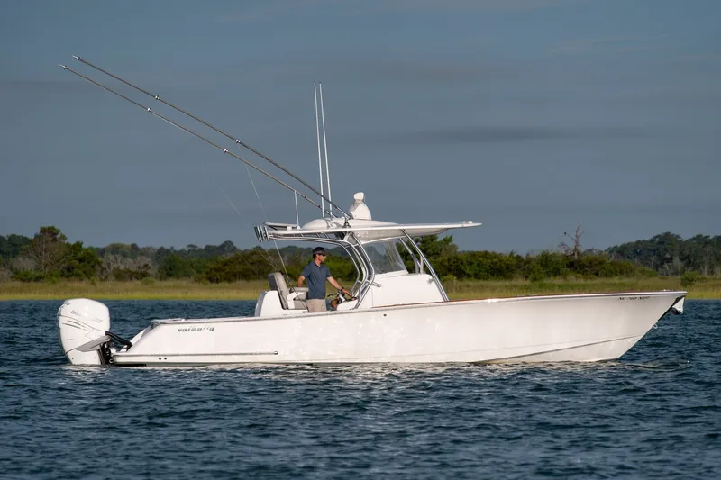 Slide: The Image of 2021 Valhalla V-33 boat cruising on a calm lake with a scenic background. - 41