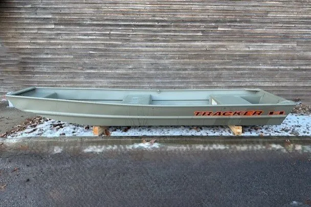 The Image of 2027 Tracker Grizzly 14 Jon boat displayed outdoors on wooden supports. - 0