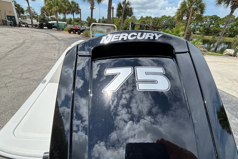 Slide: The Image of 2027 Mako Pro Skiff 17 CC with Mercury 75 engine, parked near palm trees. - 6