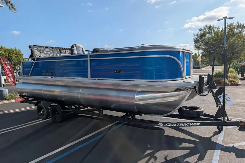 The Image of 2027 Sun Tracker Party Barge 22 RF XP3 pontoon boat on trailer in parking lot. - 0