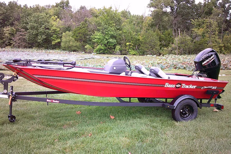 The Image of 2027 Tracker Bass Tracker Classic XL boat on trailer, parked on grass near trees. - 0