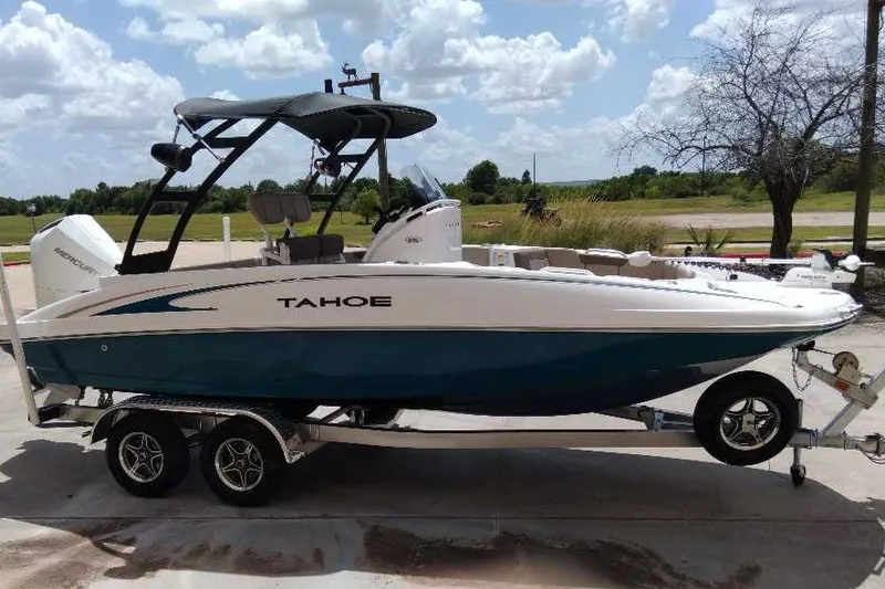 Slide: The Image of 2027 Tahoe 2150 CC boat on trailer, parked outdoors under a partly cloudy sky. - 1