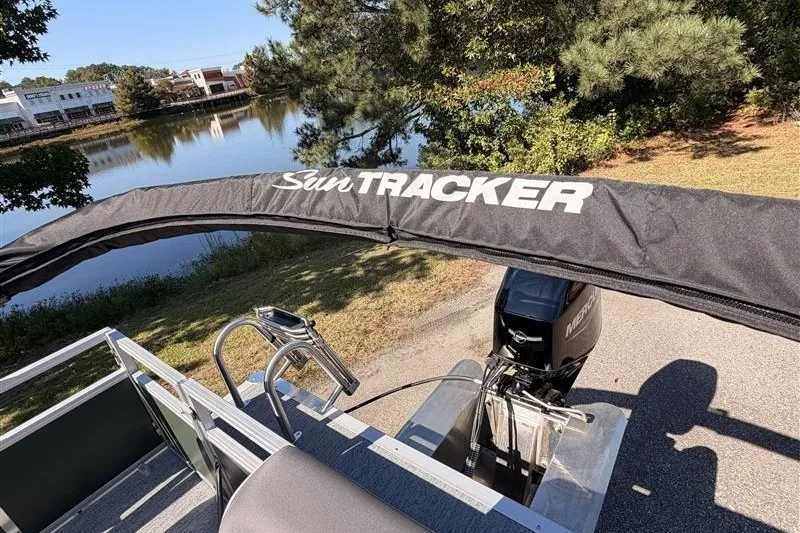 Slide: The Image of 2027 Sun Tracker Bass Buggy 16 XL Select pontoon boat by a scenic lake. - 17