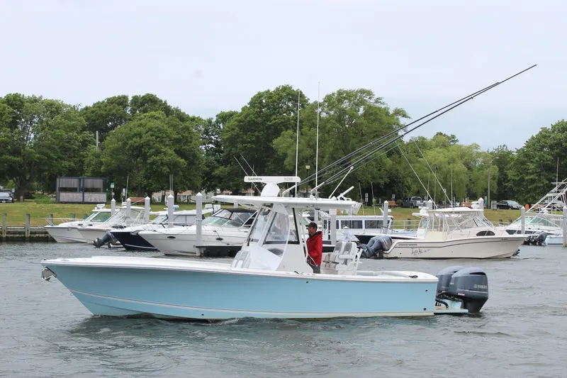 Slide: The Image of 2020 Regulator 28 Forward Seating boat on water, surrounded by other boats and greenery. - 2