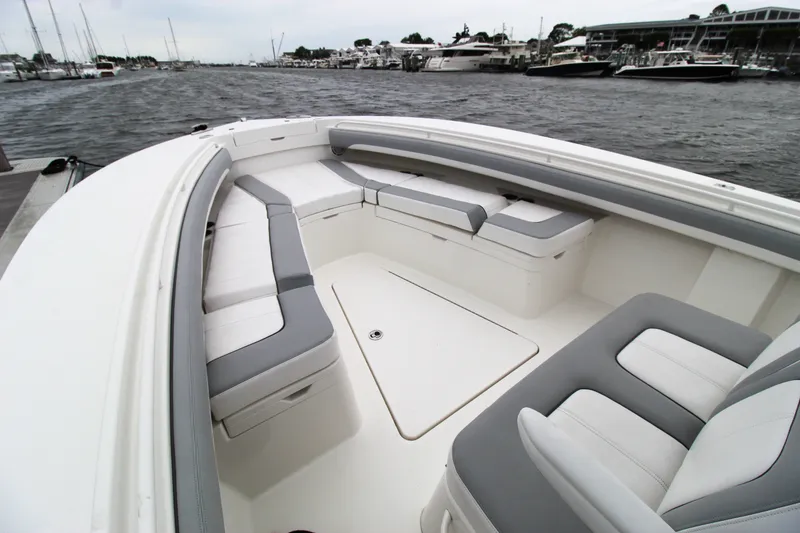 Slide: The Image of 2020 Regulator 28 Forward Seating boat with spacious, cushioned seating area on a marina. - 11