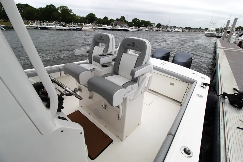 Slide: The Image of 2020 Regulator 28 Forward Seating boat docked, featuring dual helm seats and twin engines. - 16