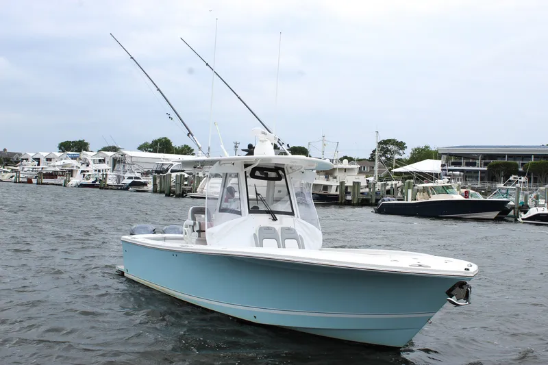 Slide: The Image of 2020 Regulator 28 Forward Seating boat docked in a marina, featuring fishing rods. - 5